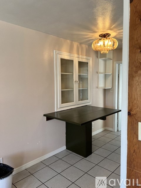 A kitchen with a black table and a chandelier.