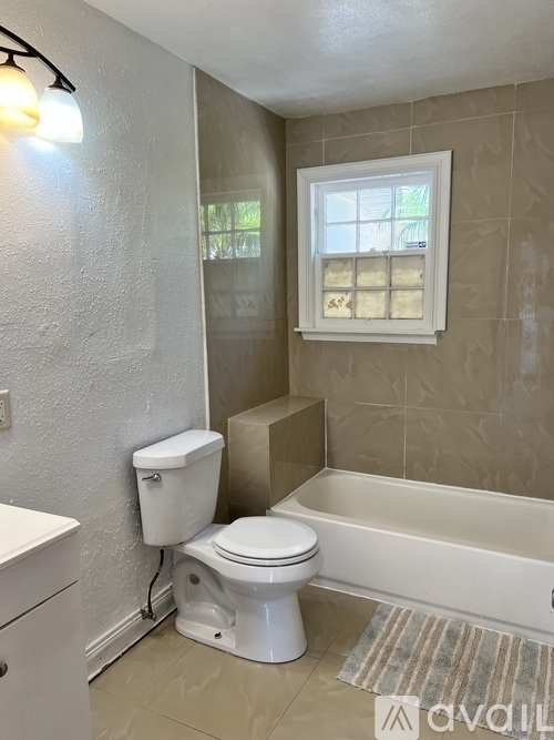 A white toilet sits in a bathroom next to a bathtub.