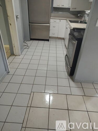 A kitchen with white tiles and a stainless steel refrigerator.