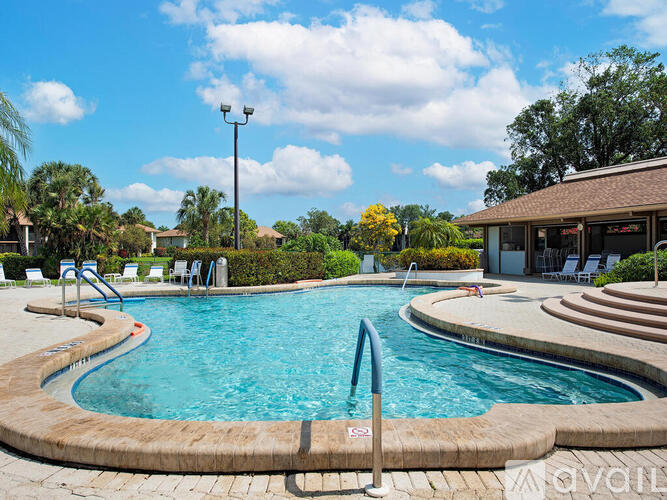 A swimming pool surrounded by a brick border and a small building in the background.