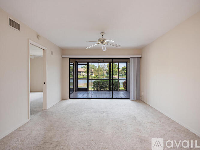 A spacious room with a ceiling fan and sliding glass doors leading to a balcony.