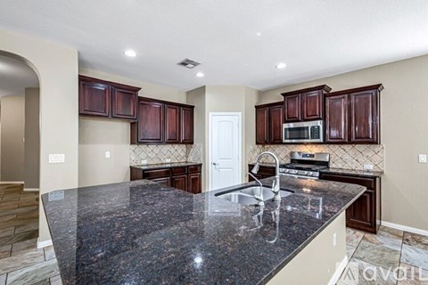 A kitchen with dark brown cabinets and granite countertops.