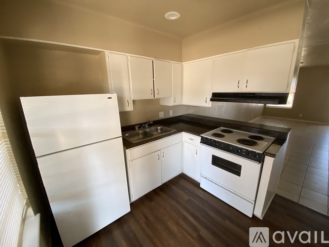 A kitchen with white appliances and wooden floors.