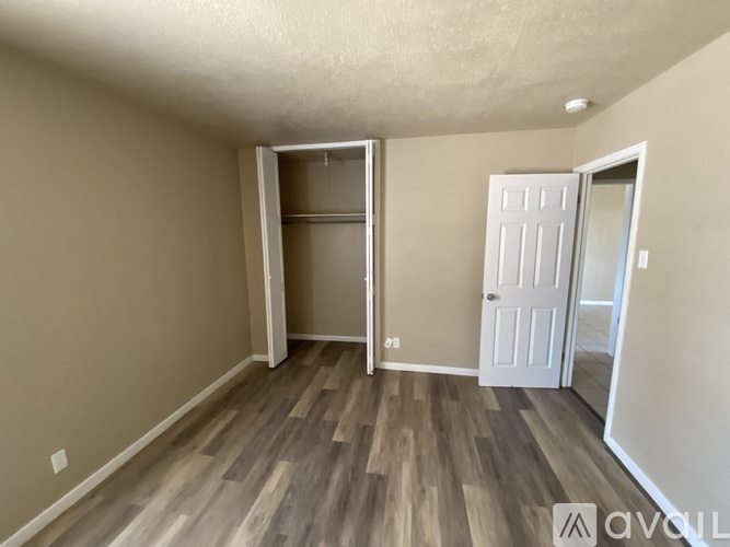 A room with a white door and wooden flooring.