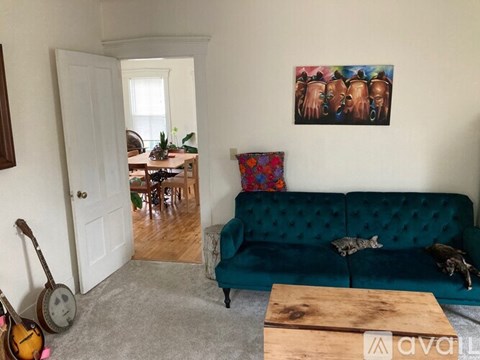 A living room with a green couch and a painting on the wall.
