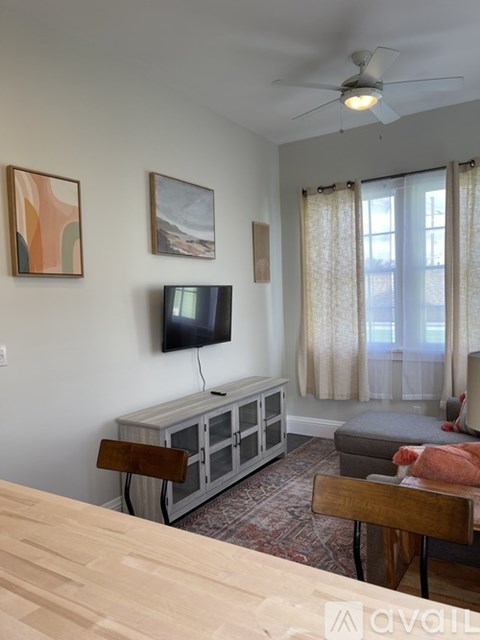 A living room with a television, a couch, and a wooden table.