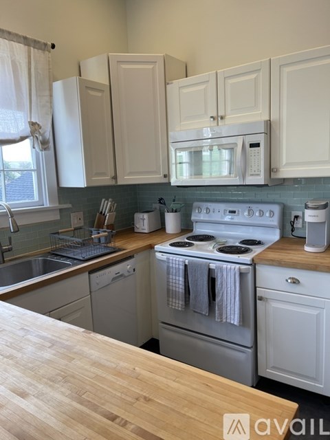 A kitchen with white cabinets and a wooden countertop.