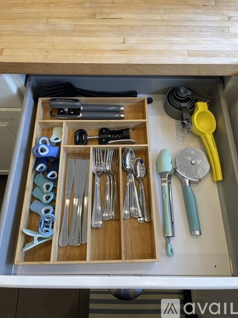 A drawer with utensils and a yellow spatula.
