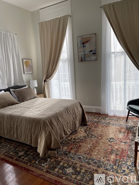A bedroom with a large bed and a rug on the floor.