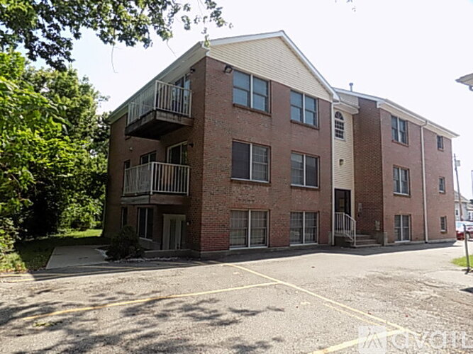 A red brick apartment building with a parking lot in front.