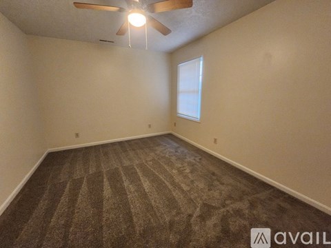 A room with a carpeted floor and a ceiling fan.