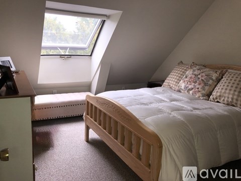 A bedroom with a bed, a window, and a carpeted floor.