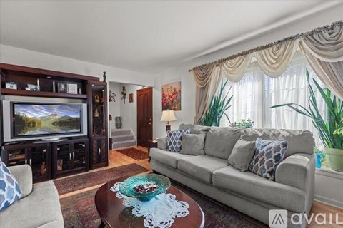 A living room with a grey couch, a coffee table with a blue cloth, a television, and a cabinet with decorative items.