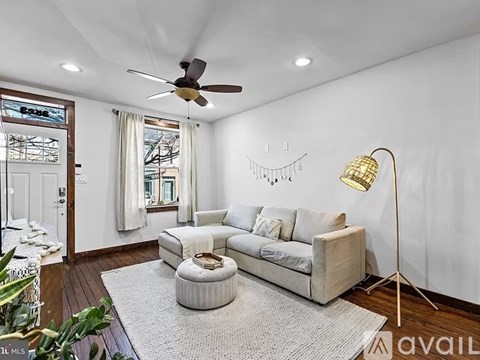 A living room with a white couch and a ceiling fan.