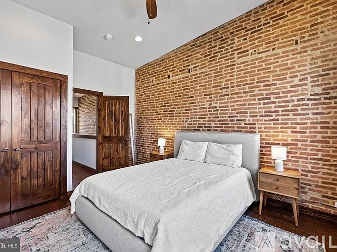 A bedroom with a brick wall and a bed.