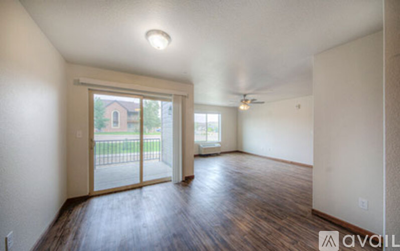 A room with wooden floors and sliding glass doors leading to a balcony.
