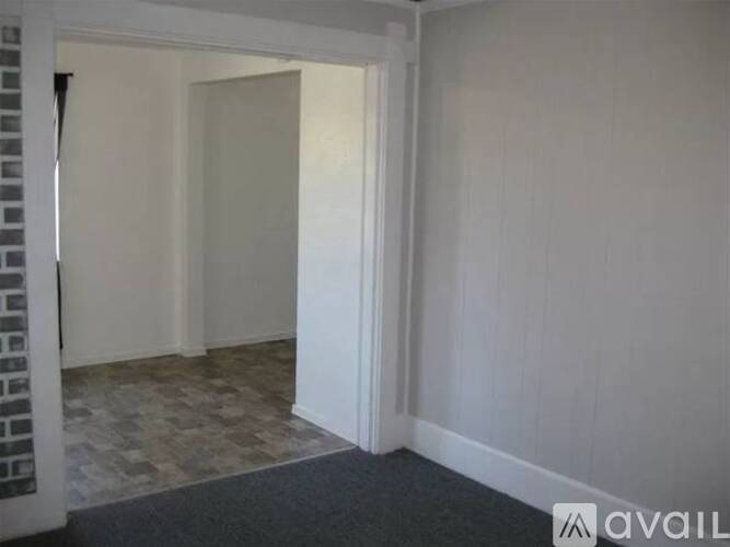 A room with a brick column and a doorway leading to another room.