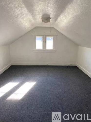 A room with a window and a carpeted floor.