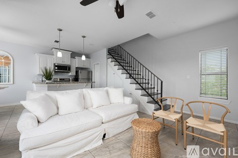A living room with a white couch and a staircase.