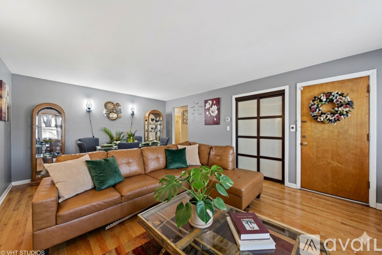 A living room with a brown leather couch and a glass coffee table.