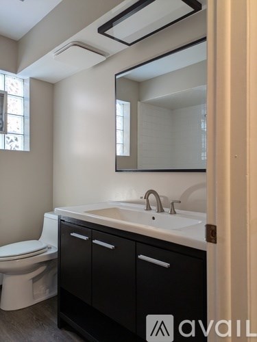 A bathroom with a sink, toilet and mirror.