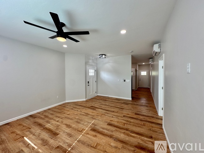 A room with a ceiling fan and wooden flooring.