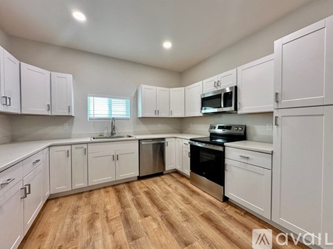 A kitchen with white cabinets and wooden floors.