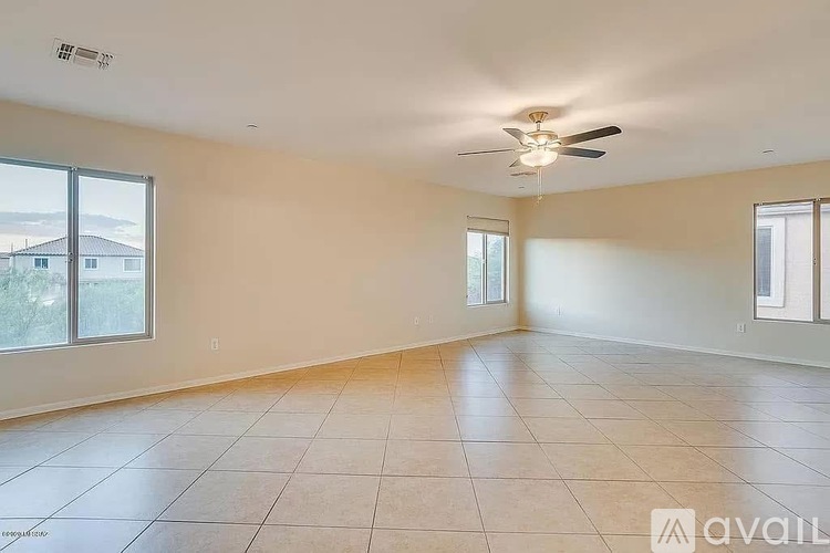A spacious room with a ceiling fan and large windows.