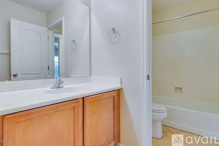 A bathroom with a white sink and wooden cabinets.