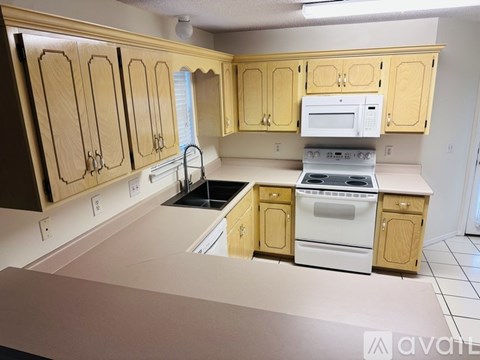 A kitchen with wooden cabinets and a white stove top oven.