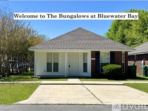 A house with a sign that says "Welcome to The Bungalows at Bluewater Bay".