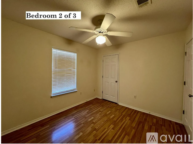 Bedroom 2 of 3 has a ceiling fan and wooden floors.