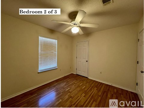 Bedroom 2 of 3 has a ceiling fan and wooden floors.
