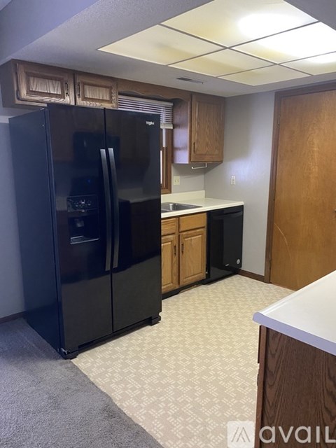 A black refrigerator in a kitchen with wooden cabinets.