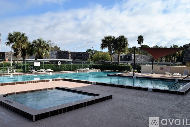 A large outdoor swimming pool with a hot tub and a red shade structure.