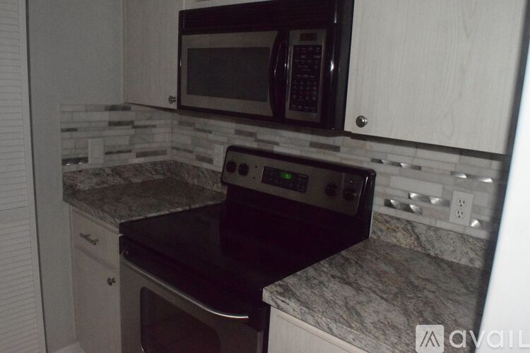 A kitchen with a black microwave and stove top oven.