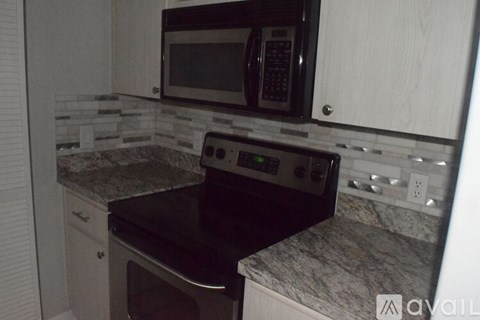 A kitchen with a black microwave and stove top oven.
