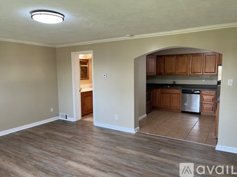 A kitchen with wooden cabinets and a refrigerator is visible through an archway.
