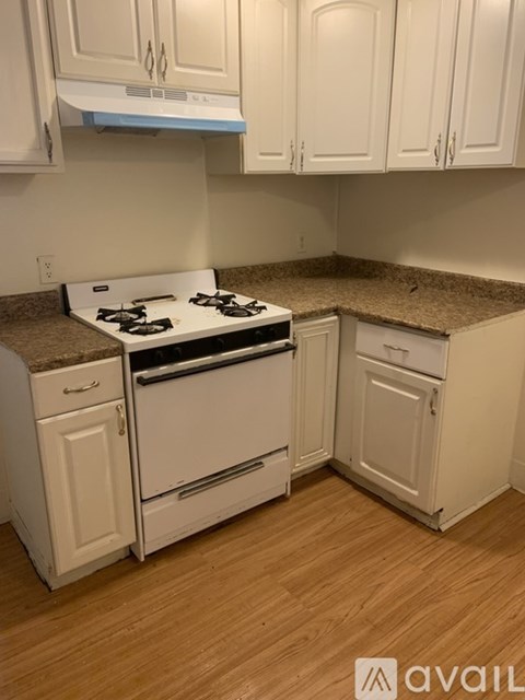 A kitchen with white cabinets and a white stove top oven.