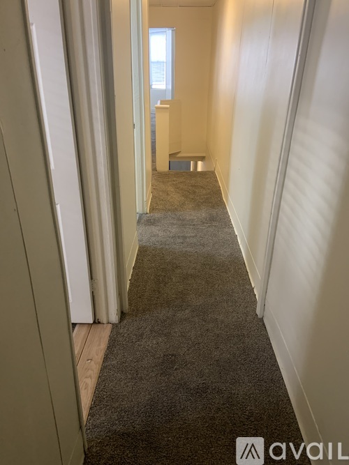 A hallway with a carpeted floor and white walls.