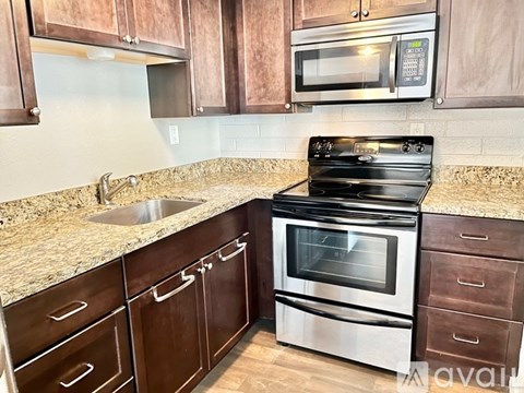 A kitchen with a black stove top oven and a microwave above it.