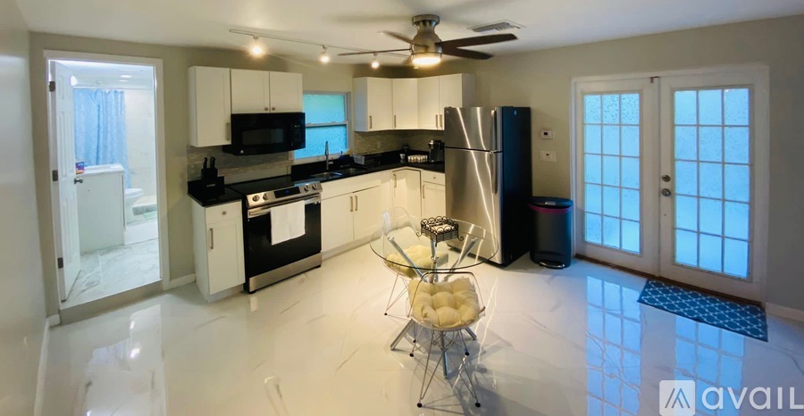 A modern kitchen with a white ceiling fan and a white table with a bowl of fruit on it.