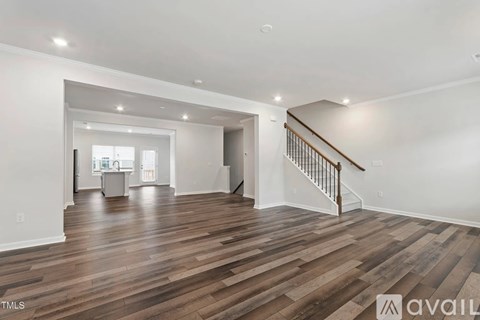 A spacious room with wooden flooring and a staircase.