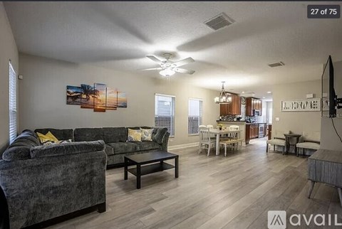A living room with a grey couch and a painting on the wall.