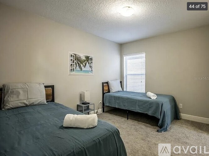 A bedroom with two beds and a nightstand with a lamp.
