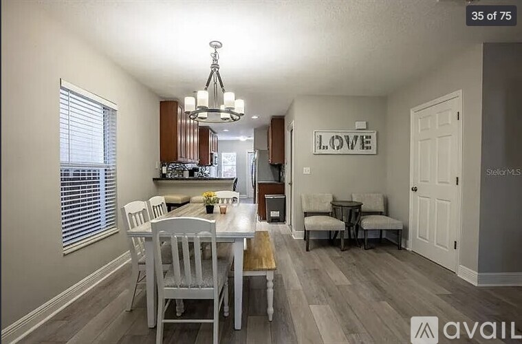 A dining room with a white table and chairs, a chandelier, and a sign that says "LOVE".