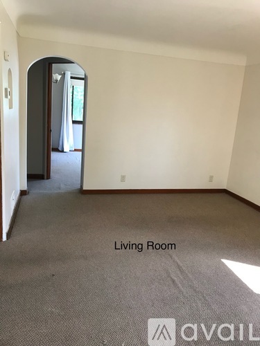 A living room with a carpeted floor and a doorway leading to another room.