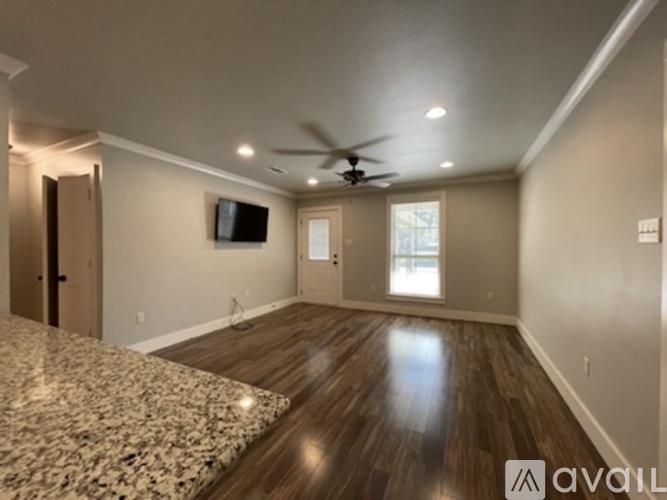 A spacious room with a ceiling fan and a flat-screen TV mounted on the wall.