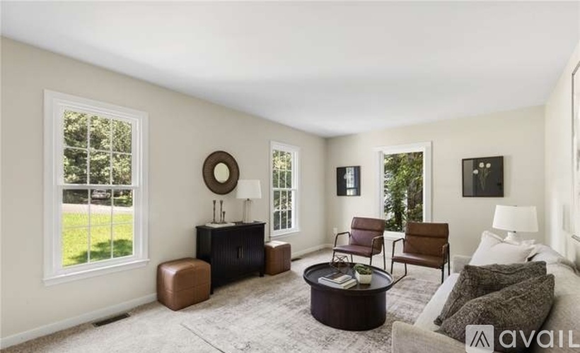 A living room with a brown chair, a brown ottoman, a white couch, and a coffee table.