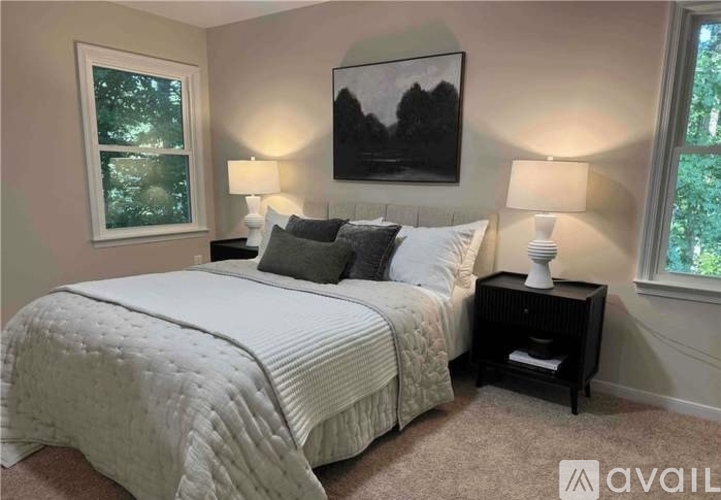A bedroom with a large bed, two lamps, and a painting on the wall.